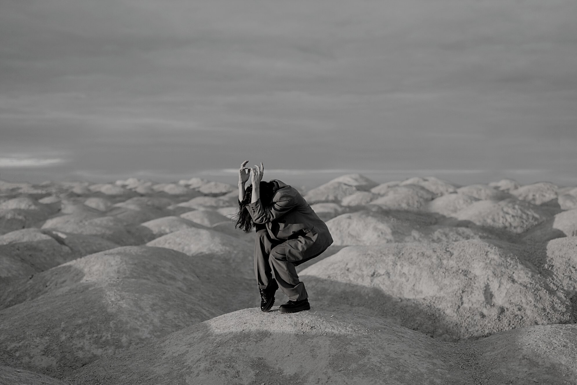 Man in Brown Jacket Sitting on Rock